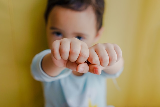 Menino com os punhos fechados apontando para a câmera.